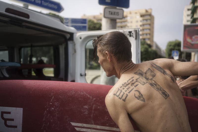 Surf Church member Andries Louw stows a surfboard in a church van in Porto, Portugal on Sunday, Aug. 18, 2024. (AP Photo/Luis Andres Henao)