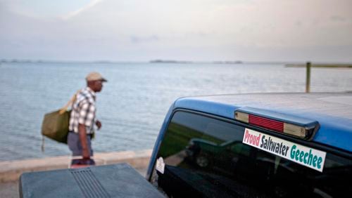 A sticker celebrating the Geechee heritage is seen on a pickup truck on June 10, 2013, as passengers board a ferry to the mainland from Sapelo Island, Ga. One of the few remaining Gullah Geechee communities in the U.S. is in another fight to hold onto land owned by residents' families since their ancestors were freed from slavery. The few dozen remaining residents of the tiny Hog Hammock community on Georgia's Sapelo Island were stunned when they learned county officials may end zoning protections enacted nearly 30 years ago to protect the enclave from wealthy buyers and tax increases. (David Goldman/AP)