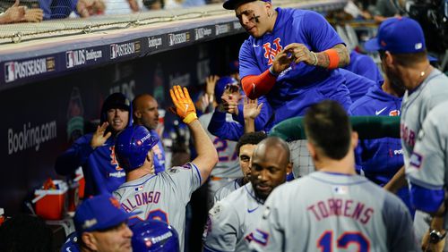 New York Mets' Pete Alonso, lower left, high fives a teammate after hitting an RBI sacrifice fly during the eighth inning of Game 1 of a baseball NL Division Series against the Philadelphia Phillies, Saturday, Oct. 5, 2024, in Philadelphia. (AP Photo/Chris Szagola)