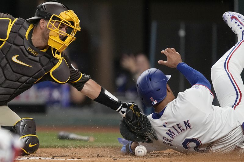 San Diego Padres catcher Kyle Higashioka loses the ball as he applies the tag on Texas Rangers' Marcus Semien, who scored on a double by Corey Seager in the third inning of a baseball game Wednesday, July 3, 2024, in Arlington, Texas. (AP Photo/Tony Gutierrez)