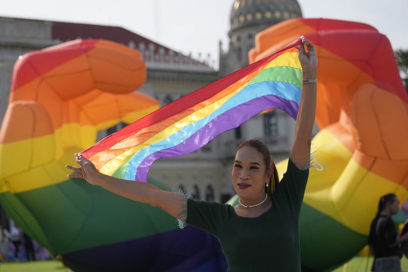 A participant holds a rainbow flag at government house in Bangkok, Thailand, Tuesday, June 18, 2024. Thailand’s Senate voted overwhelmingly on Tuesday to approve a marriage equality bill, clearing the last legislative hurdle for the country to become the first in Southeast Asia to enact such a law. (AP Photo/Sakchai Lalit)