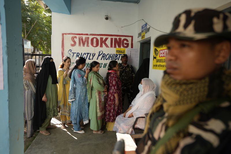 Paramilitary soldiers stand guard as people queue up to vote during the first phase of the Jammu and Kashmir assembly election, in Kishtwar, India, Wednesday, Sept. 18, 2024. (AP Photo/Channi Anand)