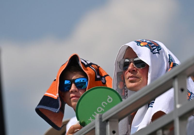 Tennis fans use a towel to provide some shade as they watch a semifinal match between Taylor Fritz and J.J. Wolf at the 2023 Atlanta Tennis Open at Atlantic Station, Saturday, July 29, 2023, in Atlanta. (Hyosub Shin / Hyosub.Shin@ajc.com)