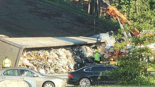 A tractor-trailer hauling trash overturned and blocked lanes on the I-285 East ramp to I-75 North early Tuesday morning.