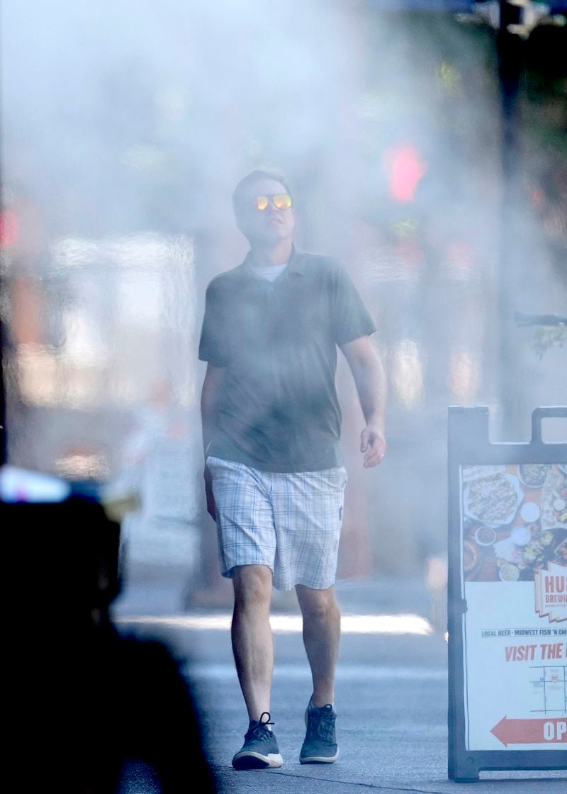 A man walks through misters on a sidewalk, Tuesday, Sept. 3, 2024, in downtown Phoenix, as 2024's endless summer has been especially hot in the city. (AP Photo/Matt York)