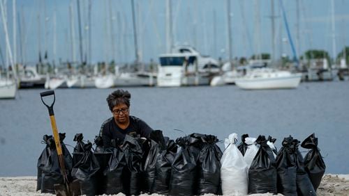 Susana Ortiz fills out sand bags on the beach at the Davis Islands Yacht Basin as she prepares for the arrival of Hurricane Milton, Tuesday, Oct. 8, 2024, in Tampa, Fla. (AP Photo/Julio Cortez)