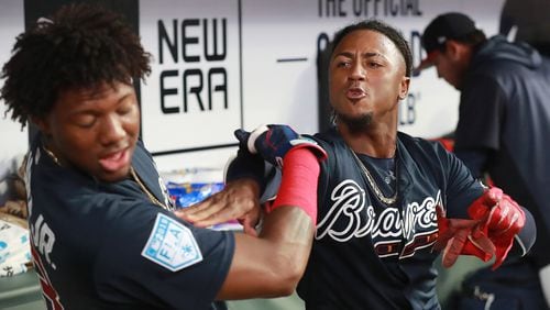 Braves infielder Ozzie Albies gives teammate Ronald Acuna a  good-natured shove in the dugout after scoring against the Cincinnati Reds during the second inning on Monday, March 25, 2019, at SunTrust Park in Atlanta.