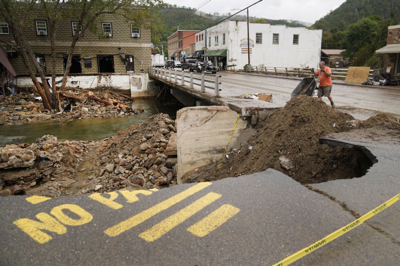 Len Frisbee dumps a wheelbarrow of dirt as he helps with clean up in the aftermath of Hurricane Helene Tuesday, Oct. 1, 2024, in Hot Springs, N.C. (AP Photo/Jeff Roberson)