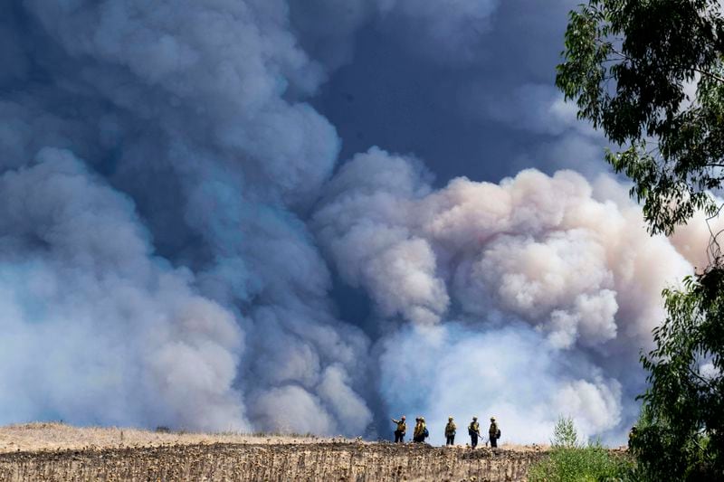 Firefighters monitor the Airport Fire from a ridge near Porter Ranch in Trabuco Canyon, Calif., Tuesday, Sept. 10, 2024. (Paul Bersebach/The Orange County Register via AP)