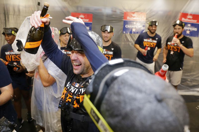 Houston Astros' Chas McCormick, center, is doused with champagne as the team celebrates in the clubhouse after defeating the Seattle Mariners 4-3 to clinch the AL West title after a baseball game Tuesday, Sept. 24, 2024, in Houston. (AP Photo/Michael Wyke)