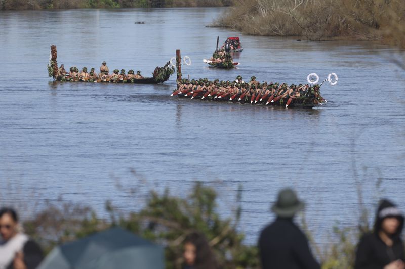 Wakas, a traditional canoe, are paddled by warriors as part of the funeral of New Zealand's Maori King, Kiingi Tuheitia Pootatau Te Wherowhero VII, in Ngaruawahia, New Zealand, Thursday, Sept. 5, 2024. (AP Photo/Alan Gibson)