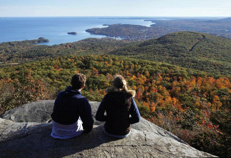 FILE - A couple takes in the view from the ocean lookout ledges of Mount Megunticook at Camden Hills State Park in Camden, Maine, on Oct. 12, 2009. (AP Photo/Robert F. Bukaty, File)