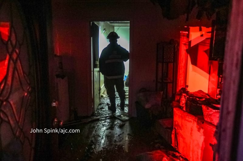 A fire investigator stands in the doorway of a house that partially burned after helping rescue a woman and her dog.