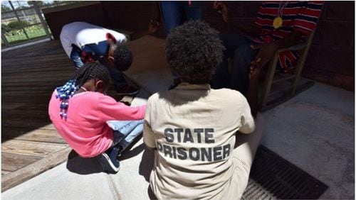 An inmate at Pulaski State Prison in Hawkinsville prays with her children in August 2016. An Emory graduate writes about escorting children to the prison to visit with their mothers.  (Hyosub Shin / AJC)