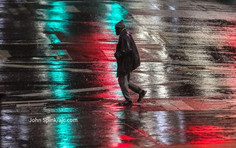 A man walks across the rain-slicked crosswalk at Peachtree and Decatur streets early Thursday.