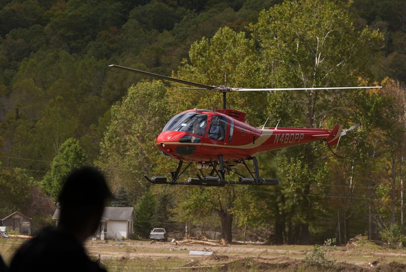 A firefighter watches as a helicopter lands at a volunteer fire station in the aftermath of Hurricane Helene, Thursday, Oct. 3, 2024, in Pensacola, N.C. (AP Photo/Mike Stewart)