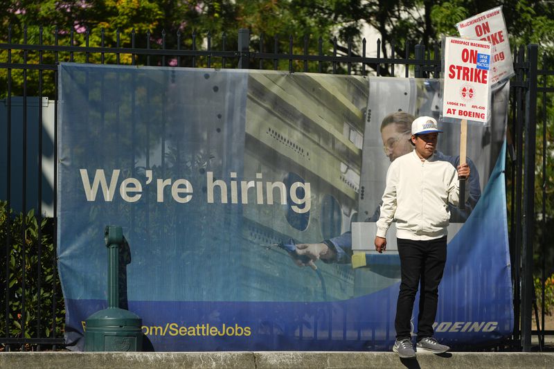 Boeing employee Som Dom, an electrician who has worked 17 years at Renton factory, holds a picket sign as workers strike Tuesday, Sept. 24, 2024, outside the company's factory in Renton, Wash. (AP Photo/Lindsey Wasson)