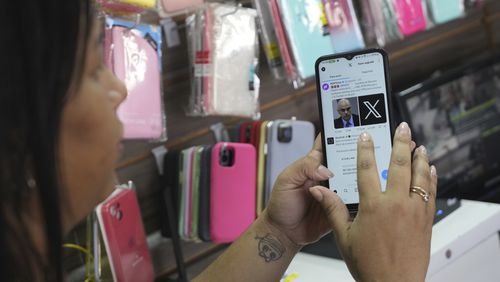 Ana Claudia, a salesperson at a cell phone case store located inside the bus station, shows the last X post she received before the social media platform was blocked nationwide in Brasilia, Brazil, Monday, Sept. 2, 2024. (AP Photo/Eraldo Peres)