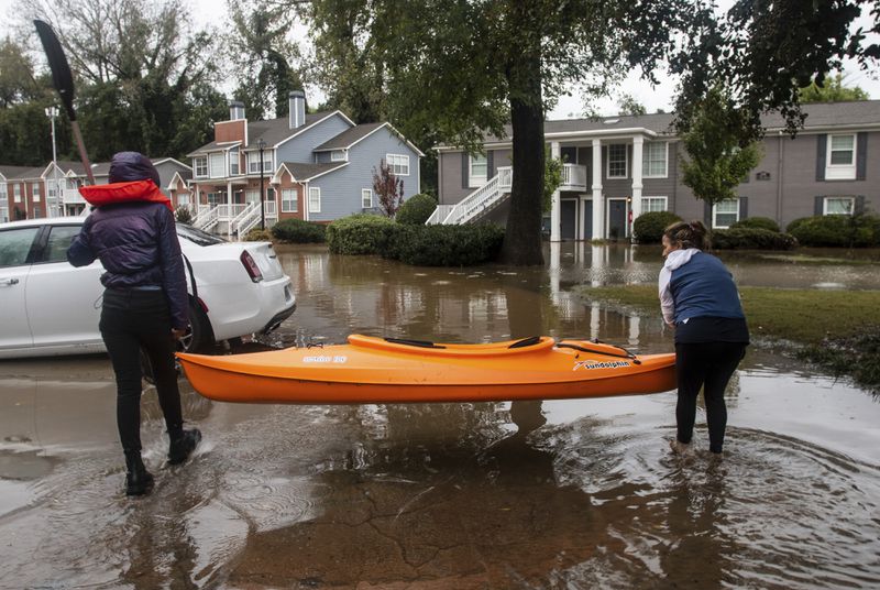 Two women maneuver a kayak into position to retrieve belongings at a flooded apartment complex after Hurricane Helene passed the area on Friday, Sept. 27, 2024, in Atlanta. (AP Photo/Ron Harris)