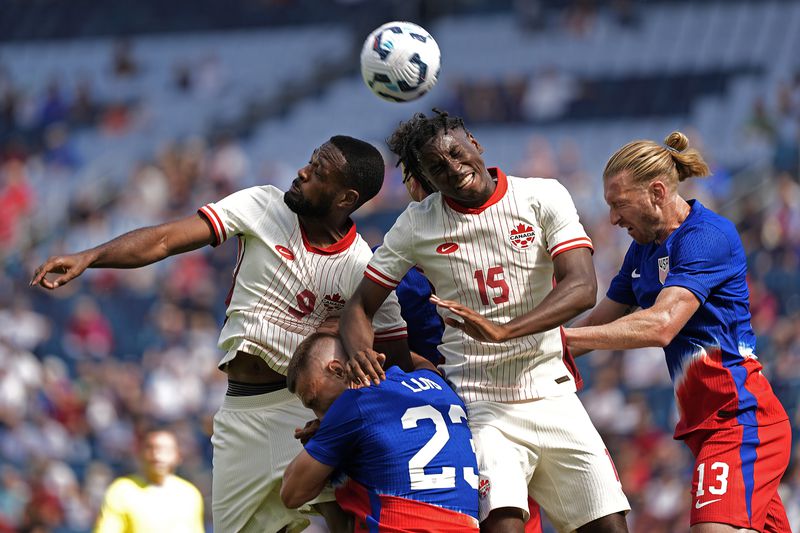 Canada forward Cyle Larin (9) and defender Moïse Bombito (15) compete for the ball with United States defenders Tim Ream (13) and Kristoffer Lund (23) during the first half of an international friendly soccer game, Saturday, Sept. 7, 2024, in Kansas City, Mo. (AP Photo/Charlie Riedel)