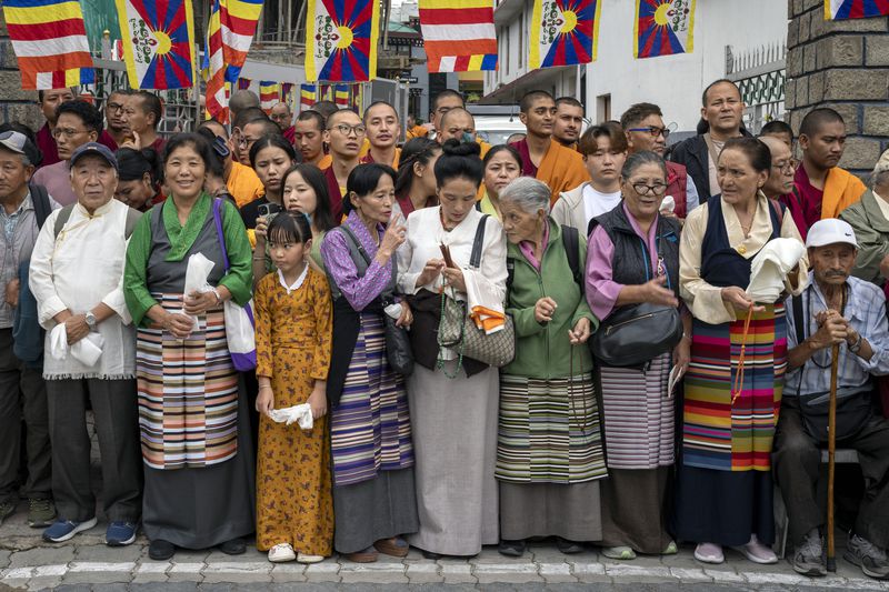 Exiled Tibetans wait with ceremonial scarves to welcome their spiritual leader the Dalai Lama before he arrived in Dharamshala, India, Wednesday, Aug. 28, 2024. (AP Photo/Ashwini Bhatia)