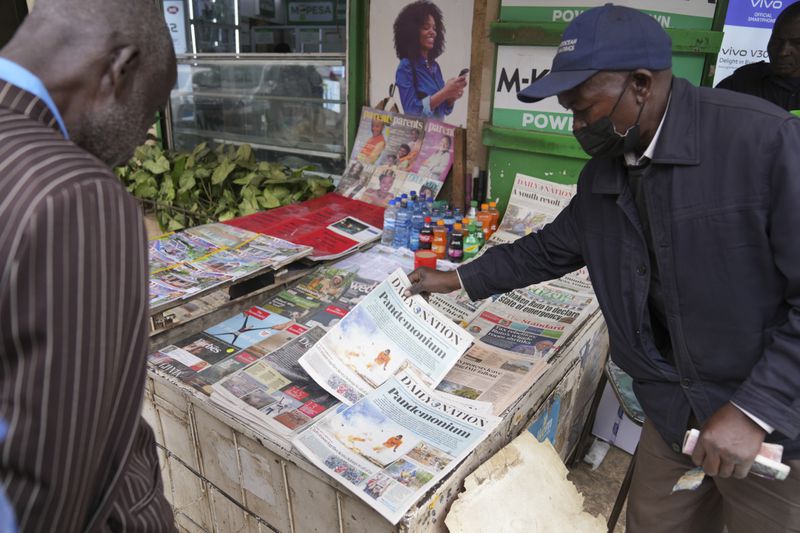 Kenyans discuss yesteday's protest as they read newspapers from a street vendor in downtown Nairobi, Kenya Wednesday, June 26, 2024. Thousands of protesters stormed and burned a section of Kenya's parliament Tuesday to protest tax proposals. Police responded with gunfire and several protesters were killed. (AP Photo/Brian Inganga)