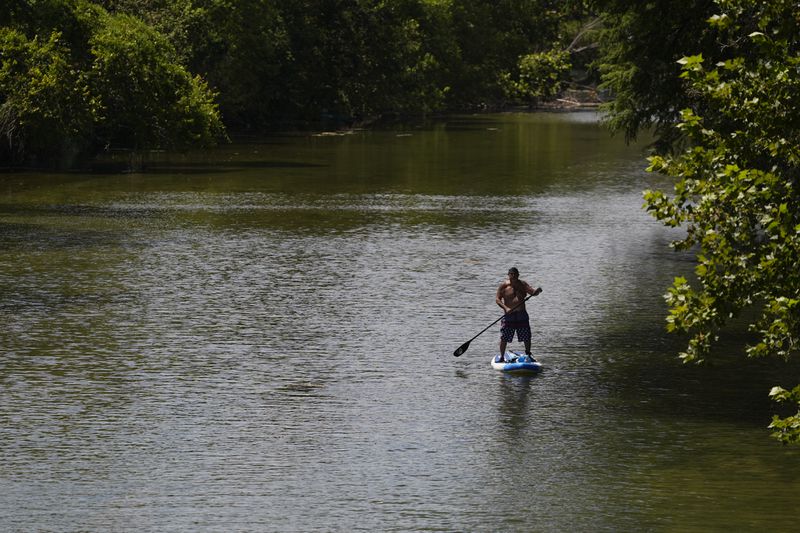 A paddler moves down the Guadalupe River as temperatures in South Texas hit triple-digit numbers, Wednesday, Aug. 21, 2024, in New Braunfels, Texas. (AP Photo/Eric Gay) Wednesday, Aug. 21, 2024, in New Braunfels, Texas. (AP Photo/Eric Gay)