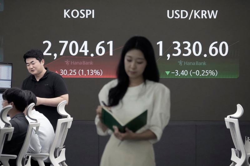 Currency traders work near a screen showing the Korea Composite Stock Price Index (KOSPI), left, and the foreign exchange rate between U.S. dollar and South Korean won at the foreign exchange dealing room of the KEB Hana Bank headquarters in Seoul, South Korea, Tuesday, Aug. 20, 2024. (AP Photo/Ahn Young-joon)