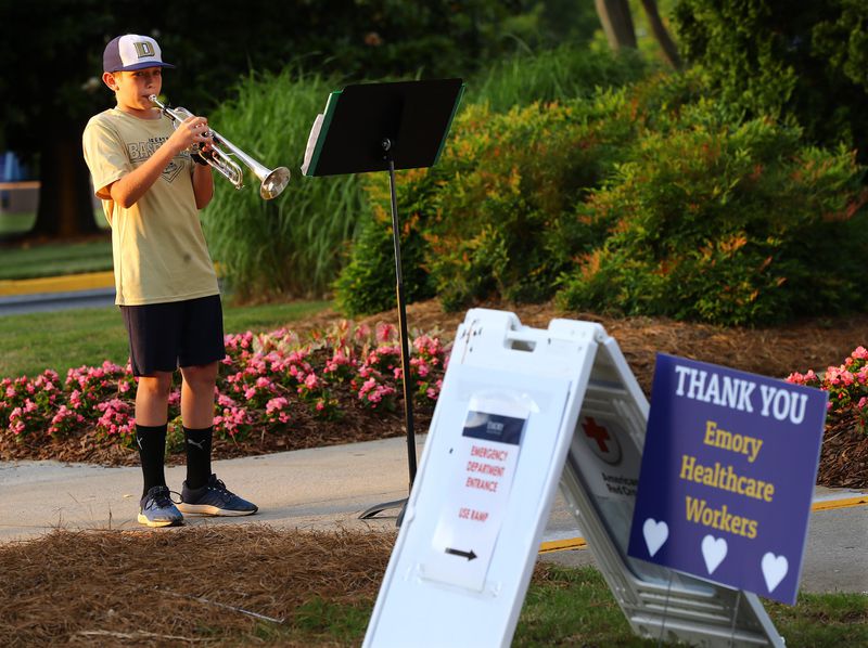 Sixth grader Jason Zgonc, whose father, Nathan Zgonc, plays the trombone with the Atlanta Symphony Orchestra, plays show tunes and classical music on his trumpet outside Emory Decatur Hospital as a way to thank the staff. CURTIS COMPTON / CCOMPTON@AJC.COM