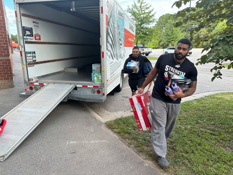 N.C. State defensive end Davin Vann, right, carries donations collected to help Hurricane Helene victims in western North Carolina, Wednesday, Oct. 2, 2024 in Raleigh, N.C. (AP Photo/Aaron Beard)