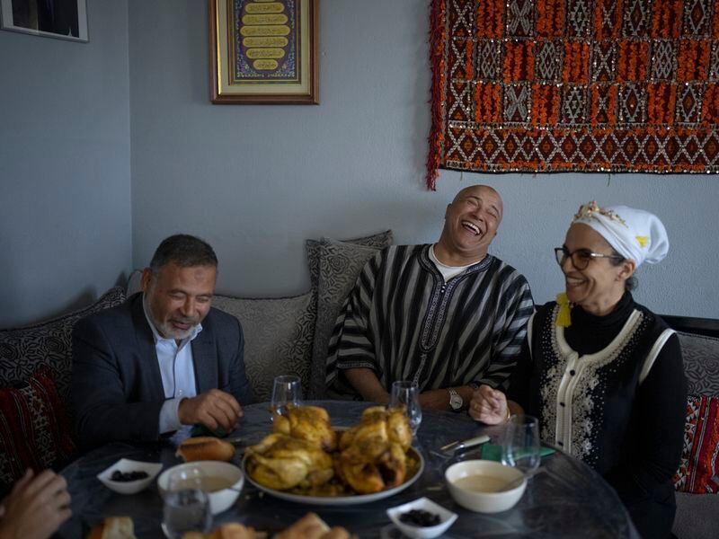 Majda Ould Ibbat, right, and her husband, Lhoussaine, center, share a meal with Imam Mohsen Ngazou, the founding director of the Ibn Khaldoun school, at their family home in Marseille, southern France, Sunday, April 21, 2024. Majda Ould Ibbat was considering leaving Marseille until she discovered Ibn Khaldoun, where her children could both freely live their faith and flourish academically. (AP Photo/Daniel Cole)