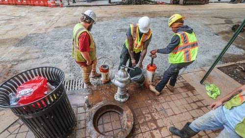 Crews covered a large hole at 11th and West Peachtree streets in Midtown as Mayor Andre Dickens announced Wednesday that water service has been restored.