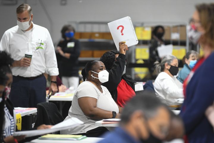 A election worker holds up a card to get the attention of an election official as she and her partner count ballots as votes for President are recounted at the Gwinnett County elections office on Friday, Nov.13, 2020 in Lawrenceville. (JOHN AMIS FOR THE ATLANTA JOURNAL-CONSTITUTION)