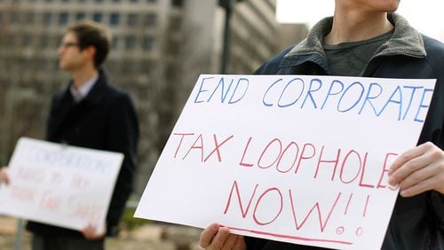 A Georgia Fair Share intern holds a sign protesting corporate tax loopholes during a Georgia Fair Share rally near the Coca-Cola headquarters on North Avenue.