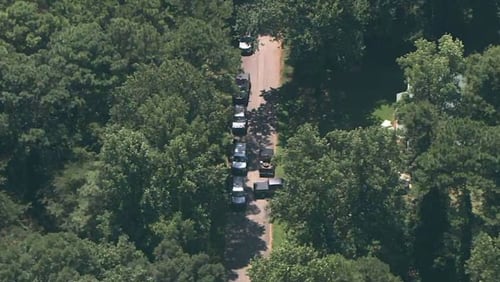 Law enforcement vehicles crowd on Linden Lane where a murder suspect barricaded himself inside a Stockbridge home after shooting a U.S. marshal attempting to serve a warrant.