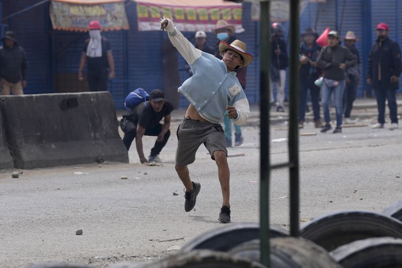 A supporter of President Luis Arce throws a stone at supporters of former President Evo Morales as the two groups face off in El Alto, Bolivia, Sunday, Sept. 22, 2024. (AP Photo/Juan Karita)