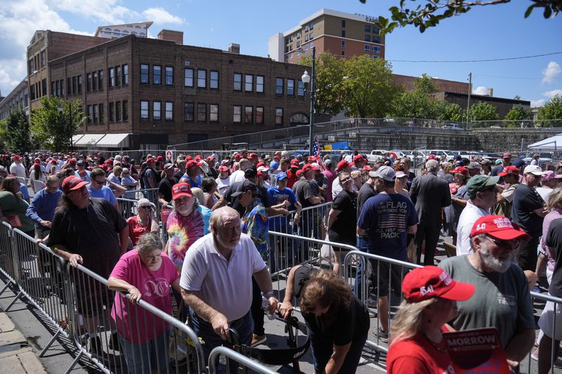 People wait to line to attend campaign rally with Republican presidential nominee former President Donald Trump in Asheville, N.C., Wednesday, Aug. 14, 2024. (AP Photo/Matt Rourke)