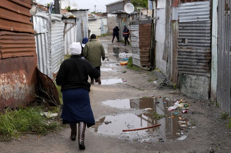 People make their way through drenched passages in Khayelitsha, Cape Town, South Africa, Thursday July 11, 2024. The South African city of Cape Town and surrounding areas have been hit by more storms, ripping roofs off houses and causing widespread flooding. (AP Photo/Nardus Engelbrecht)