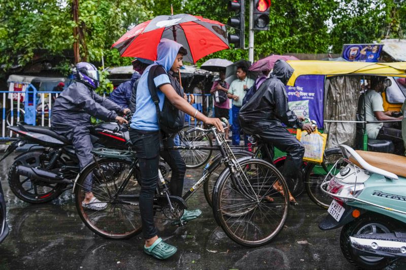 Commuters wait during a traffic jam in Kolkata, India, as rain continues after cyclone Remal made a landfall near Bangladesh-India border, Monday, May 27, 2024. (AP Photo/Bikas Das)