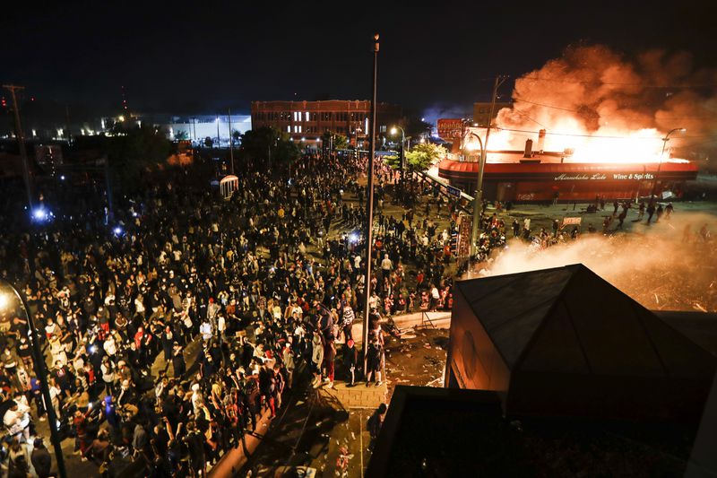 FILE - Protestors demonstrate outside of a burning Minneapolis 3rd Police Precinct, Thursday, May 28, 2020, in Minneapolis, in the wake of the death of George Floyd, a black man who died in police custody earlier in the week. (AP Photo/John Minchillo, File)