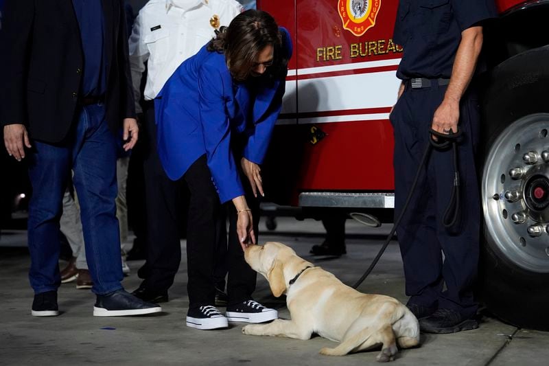 Democratic presidential nominee Vice President Kamala Harris greets a dog and members of the Aliquippa City Fire Department during a campaign stop at a fire house, Sunday, Aug. 18, 2024, in Aliquippa, Pa. (AP Photo/Julia Nikhinson)