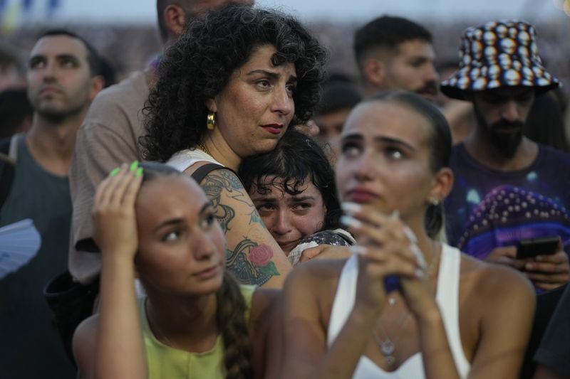 A young woman is comforted as she weeps at the Nova Healing Concert in Tel Aviv, Israel, on Thursday, June 27, 2024. This was the first Tribe of Nova mass gathering since the Oct. 7, 2023 cross-border attack by Hamas that left hundreds at the Nova music festival dead or kidnapped to Gaza. (AP Photo/Ohad Zwigenberg)