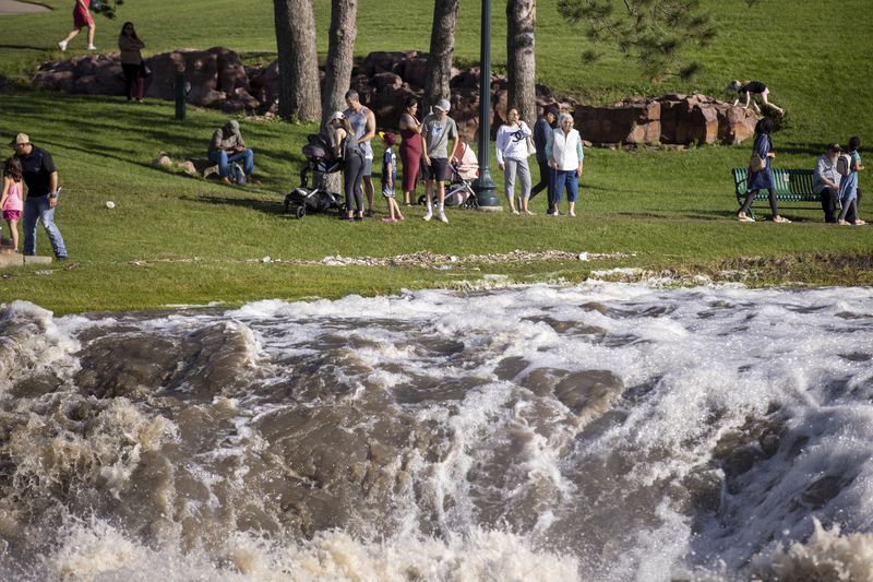 Families embark on Falls Park as water rose quickly after days of heavy rain led to flooding in the area, Saturday, June 22, 2024, in Sioux Falls, S.D. (AP Photo/Josh Jurgens)