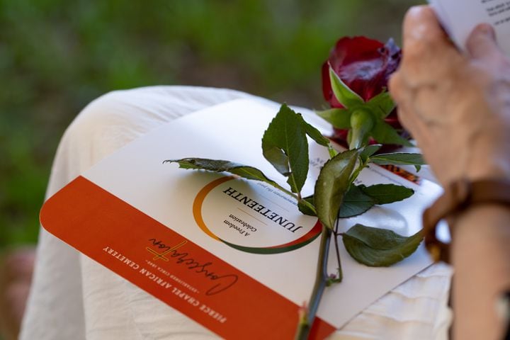 A program and rose sit on a woman’s lap during a Juneteenth celebration Monday, June 20, 2022 in Midland, outside Columbus, where the Pierce Chapel African Cemetery was reconsecrated. Ben Gray for the Atlanta Journal-Constitution