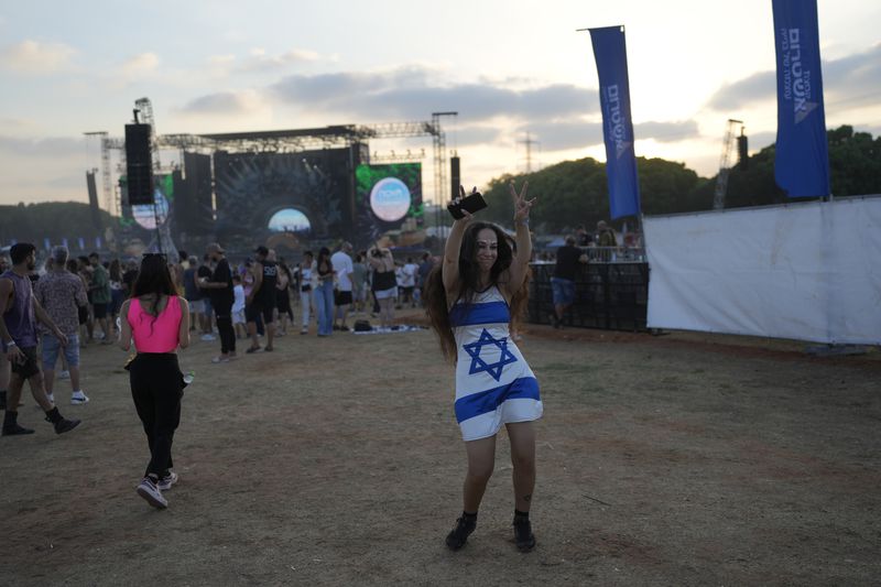 A woman wears a dress in the colors of the Israeli flag at the Nova Healing Concert in Tel Aviv, Israel, on Thursday, June 27, 2024. This was the first Tribe of Nova mass gathering since the Oct. 7, 2023 cross-border attack by Hamas that left hundreds at the Nova music festival dead or kidnapped to Gaza. (AP Photo/Ohad Zwigenberg)