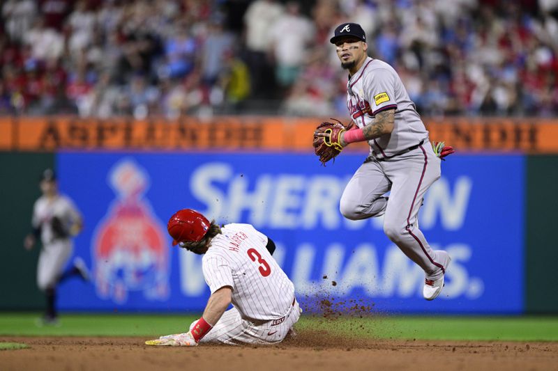 Atlanta Braves' Orlando Arcia, right, leaps after a force out against Philadelphia Phillies' Bryce Harper (3) during the ninth inning of a baseball game, Sunday, Sept. 1, 2024, in Philadelphia. (AP Photo/Derik Hamilton)