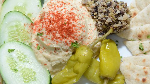Hummus and Olive Tapenade are served as one appetizer - both on a plate with pita wedges and vegetables — at Front Page News.
