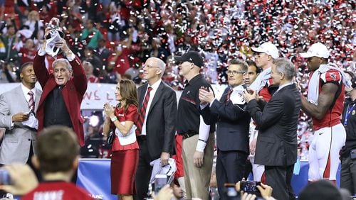 Falcons owner Arthur Blank hoists the NFC championship trophy with (from left) Rich McKay, Dan Quinn, Thomas Dimitroff, Matt Ryan and Julio Jones looking on. (Curtis Compton/ccompton@ajc.com)