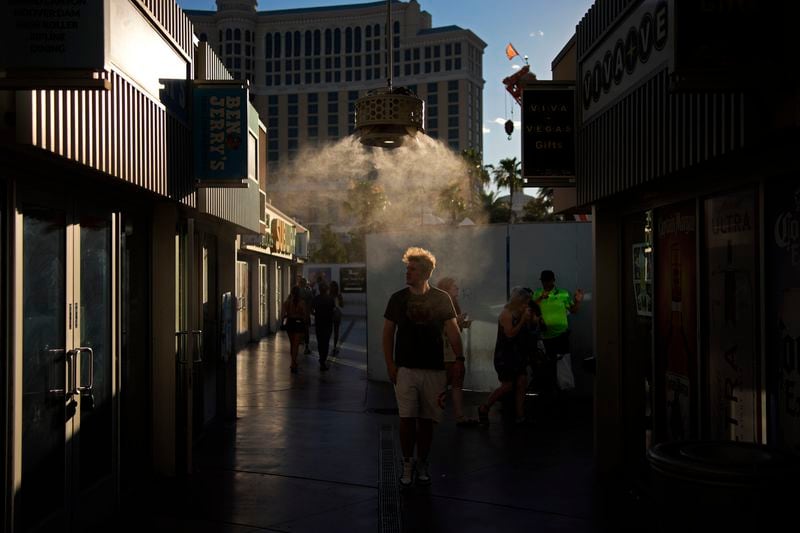 People walk through misters along the Las Vegas Strip, Sunday, July 7, 2024, in Las Vegas. The city set an all time record high of 120 F (48.8 C) Sunday as a heat wave spread across the Western U.S. sending many residents in search of a cool haven from the dangerously high temperatures. (AP Photo/John Locher)