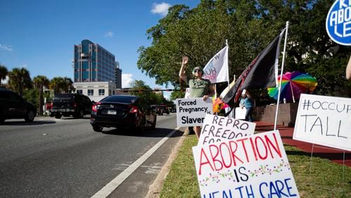 FILE - A small crowd holding signs and waving as cars pass by the Leon County Courthouse, protests Sb 300, which bans abortions after six weeks, Thursday, April 13, 2023. in Tallahassee, Fla. (Alicia Devine/Tallahassee Democrat via AP)